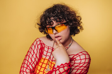 Vibrant fashion portrait with a model in playful attire and sunglasses against a bright yellow...