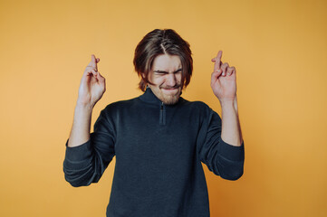 Young man expressing excitement and hope against a vibrant yellow background