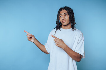Young man in casual white shirt gestures towards something interesting against a blue background