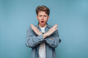 Young man expresses strong emotions with an intense gesture against a blue background