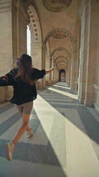 Happy tourist woman running and rejoicing on the streets of Paris. The capital of France, beautiful historical architecture, travel in Europe.