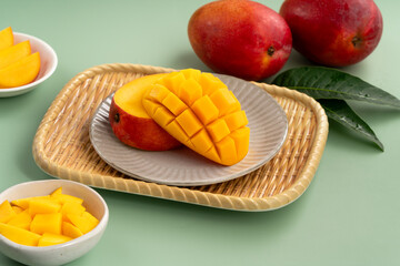 Fresh ripe mango with cubes on green table background.