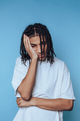 Teen boy expressing frustration while resting his head on his hand against a blue background
