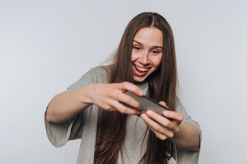 Excited young woman enjoys gaming on her smartphone in a cozy indoor setting during the afternoon