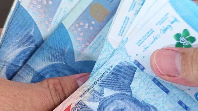Counting Indonesian Rupiah CloseUp of Hands Handling Banknotes Financial Transaction.