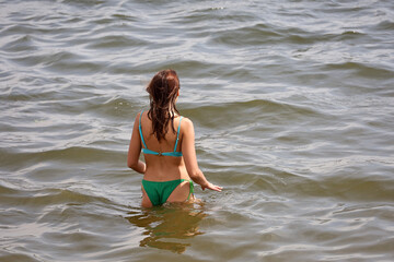 Young woman in bikini going to swim in water, beach vacation in summer