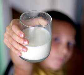 Young Child's Hand Holding Up a Glass of Fresh White Milk