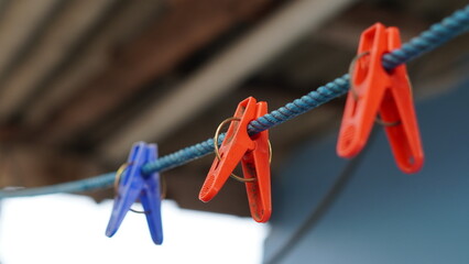Close-up of vibrant plastic clothespins on a blue rope with a soft background, showcasing household...