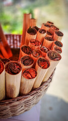 Close-up of traditional betel nut parcels in bamboo tubes, displayed in a woven basket in Cambodia....