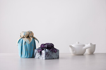 Elegant Korean table setting with traditional Korean bojagi gift wrapping for Chuseok, ceramic vase and fabric, tree branches.