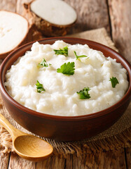 A close-up of bomb� (cassava flour porridge), a thick, white, comforting staple food, served in a simple bowl.