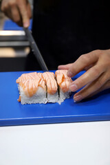 chef cortando un rollo de sushi de salmón ahumado con arroz para degustar