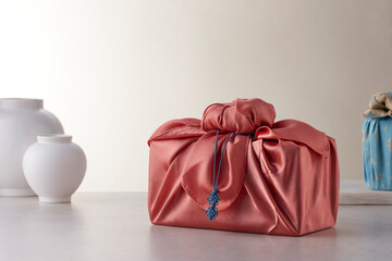 Elegant Korean table setting with traditional Korean bojagi gift wrapping for Chuseok, ceramic vase and fabric, tree branches.