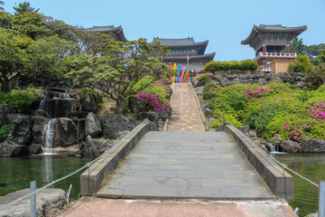 Traditional Korean temple with a stone path, waterfall, and colorful lanterns in spring, Jeju Island, South Korea.