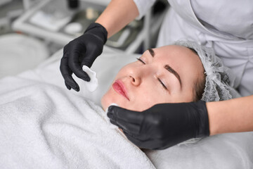 Young woman receives soothing facial treatment in spa. Atmosphere is serene, emphasizing...