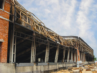 A building shows the devastating effects of a fire with a collapsed roof and charred structure.