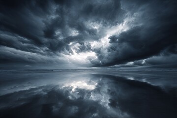 A powerful, dark sky reflected in the wet sand of a beach.
