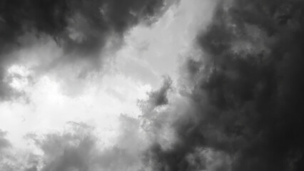 Black and white image of dramatic storm clouds swirling in the sky, creating a high-contrast, moody atmosphere.