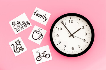 Wall clock and many paper cards with hand drawing of different life activities, top view. Time...