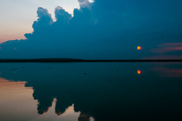The sunset paints the sky over a still lake, creating a perfect, mirrored reflection. A tranquil...
