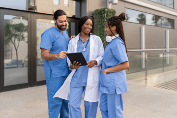 Multiracial diverse Medical team discussing patient information using tablet outside hospital