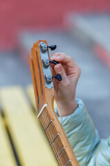 Child tuning guitar by hand outdoors