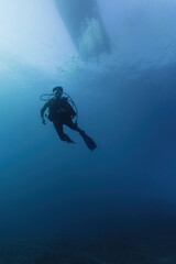 Scuba diver descending deep from boat in the ocean. Underwater sport in the sea