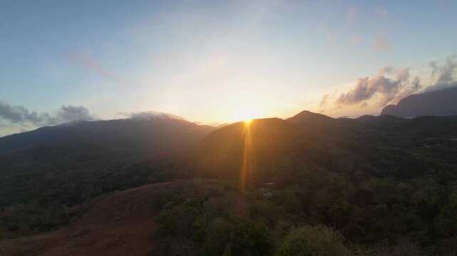 Forward drone sweep greets the rising sun as warm rays crown golden grass hills of Mount Tapyas, unveiling mist-veiled valleys and jagged peaks around Coron Island, Palawan.