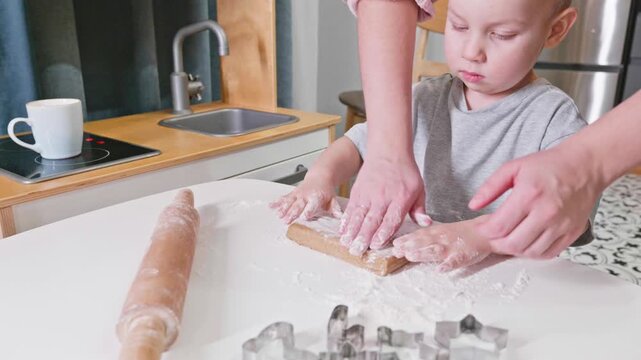 A child prepares rolling dough on a white table, with cookie cutters nearby. The scene reflects the charm of childhood creativity and festive baking fun.