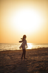 Fototapeta premium Silhouetted Woman with Ukulele Enjoying Sunset on Beach 