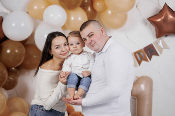 Family celebration with parents and child in a festive setting adorned with balloons