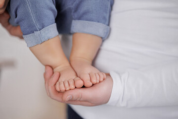 Parent gently holding a child's feet in a cozy indoor setting during a warm afternoon
