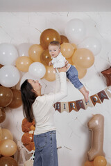 Mother holds her baby boy during a joyful birthday celebration at home