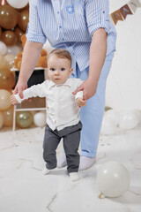 Toddler takes first steps in celebratory indoor setting with balloons and decorations