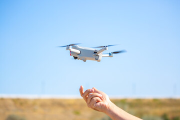 Quadcopter in flight against the sky. A small drone takes off from a person's hand.