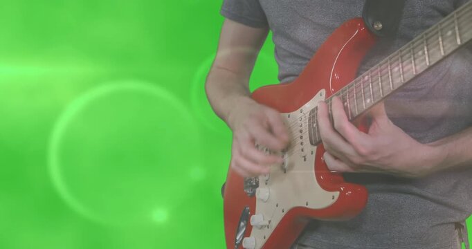 Musician bringing guitar and strumming chords showing music on green-screen with light overlays