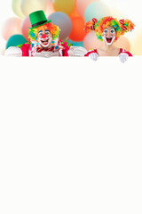 Funny clowns peeking out from behind sign blank template mock up for advertising, posters, greetings, invitations. Entertainers as Joker in a suit and wig, with clown whiteface makeup.