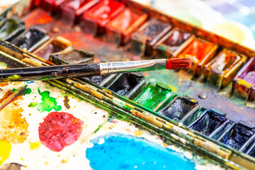 Watercolor paint in old used plastic palettes, brushes, creative mess