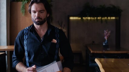 An elegant businessman enters a cozy coffee shop carrying a laptop, documents, and a diary, preparing to start his workday. - Powered by Adobe