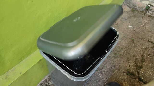 Throwing plastic bottle into the gray trash can