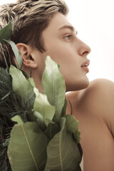 Profile Portrait Of Young Man Holding Greenery Bouquet In Soft Natural Light 
