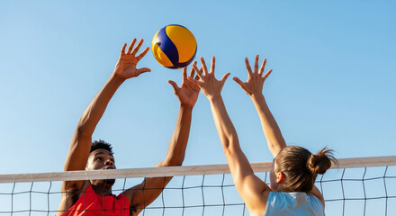 Low -angle shot of two volleyball players, male and female, blocking a ball over the net against a clear blue sky