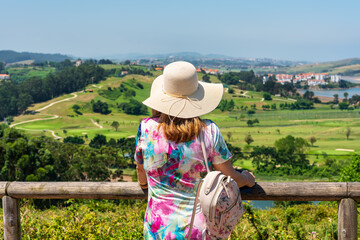 Woman with hat enjoying the views of the typical landscape of northern Spain, Cantabria.