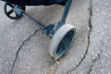 Asphalt surface with dent and hole trapping stroller wheel, need for regular road maintenance and...