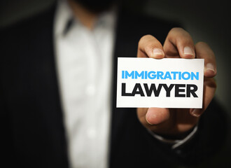 Immigration Lawyer showing his business card towards screen close up, man standing in black and white dress. Lawyer, immigration, judiciary