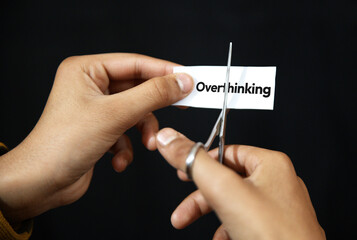 Overthinking habit cutting concept with hand showing close up of paper with scissor