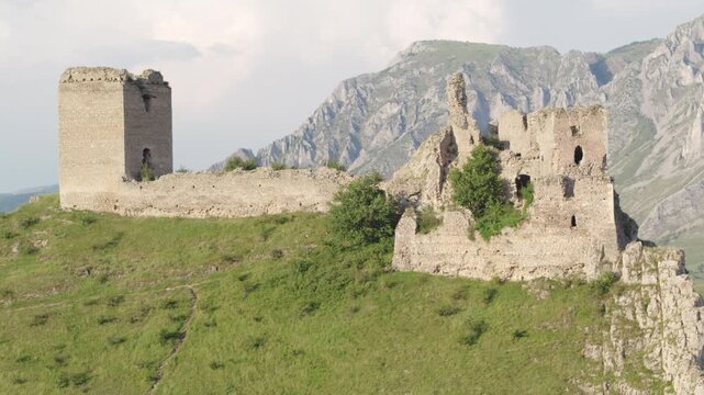 Cinematic drone shot slowly ascending to reveal the medieval Trascău Fortress ruins in Colțești, Romania. An epic historical landmark in the mountains of Transylvania.