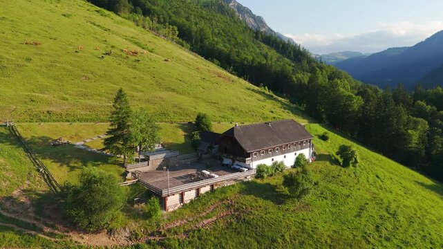 Aerial: Laimeralm mountain hut Inn above Lake Wolfgang at sunset with golden hour light in Austria, orbit drone shot