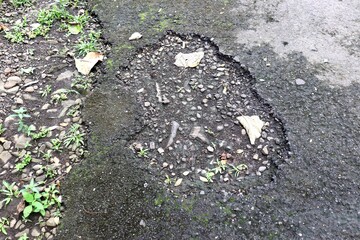 A pothholes in the asphalt road. A damaged road in the countryside that needs repair. The road...