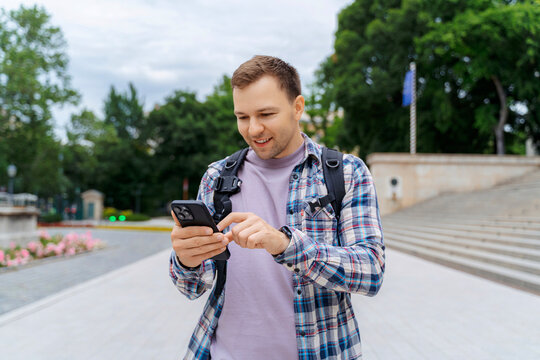 Young male tourist using smartphone in city park